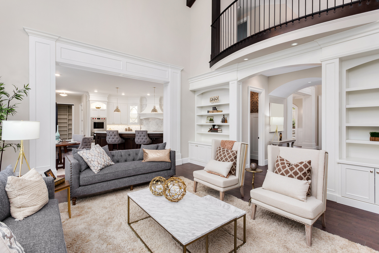 Beautiful living room interior with tall vaulted ceiling, loft area, hardwood floors and fireplace in new luxury home. Has view of kitchen and dining area, and loft. Redone by interior designer